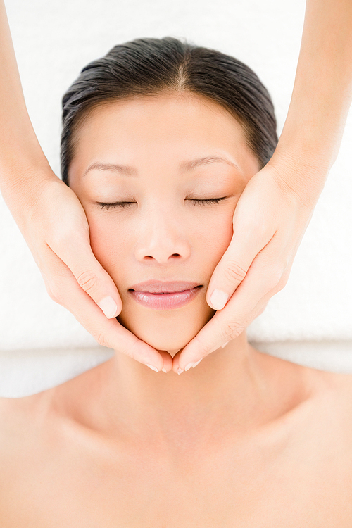 High angle view of an attractive young woman receiving facial massage at spa center