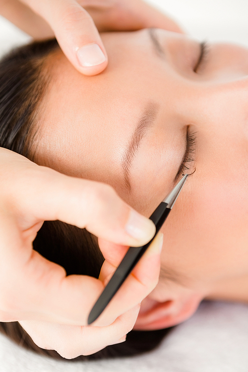 Woman placing fake eyelash on a patient at the spa health