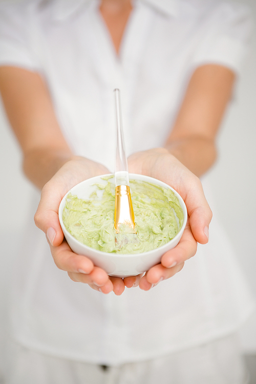 Woman having green cream to do a masage at spa center