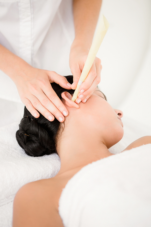 Close up of a beautiful young woman receiving ear candle treatment at spa center