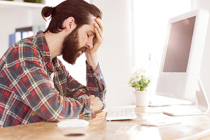 Hipster businessman stressed at his desk in his office