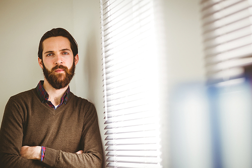 Hipster businessman leaning beside window in his office