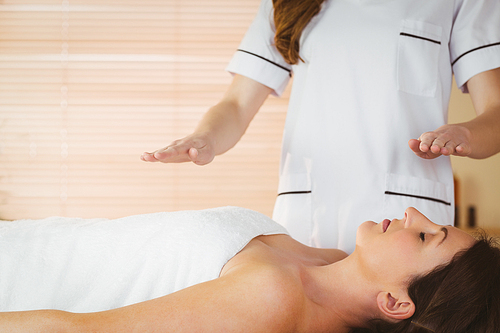 Young woman having a reiki treatment in therapy room