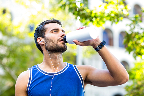 An handsome athlete drinking water on a sunny day