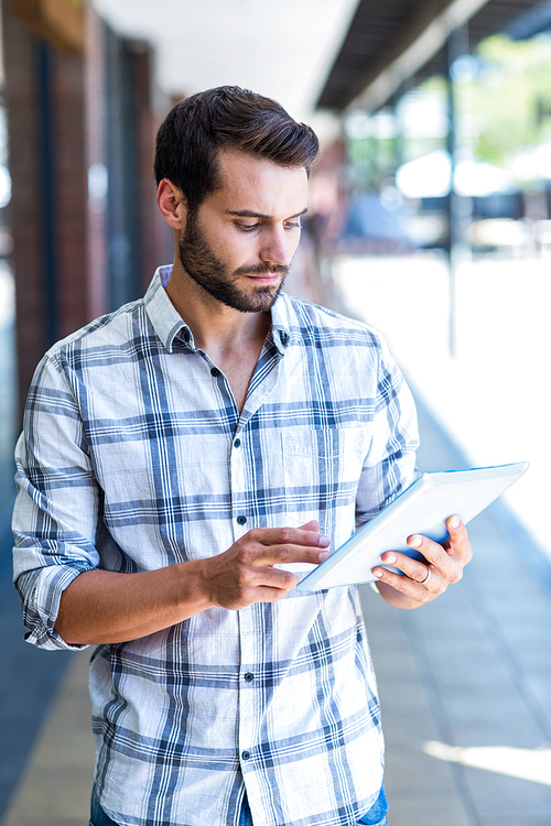 Hipster man using tablet computer in the city on a sunny day