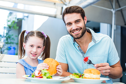 Daughter and father eating at the restaurant on a sunny day