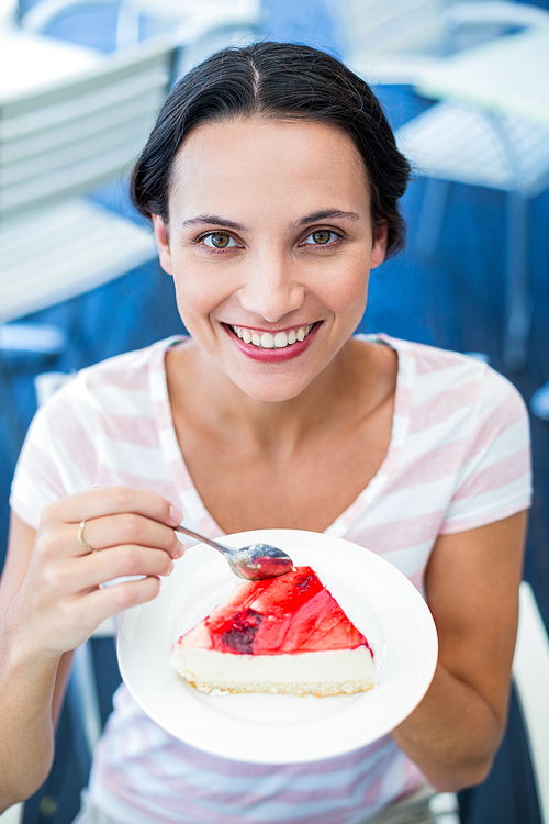 Smiling brunette taking a piece of chocolate cake at the cafe