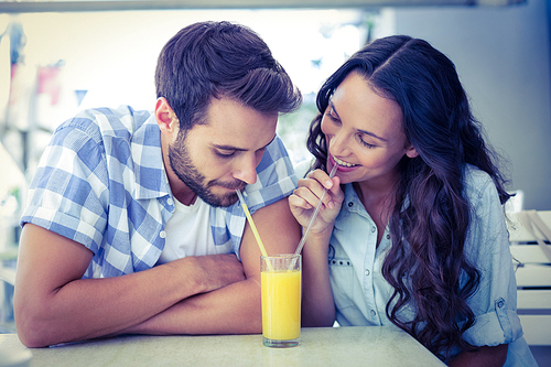 Cute couple drinking an orange juice together in a cafe