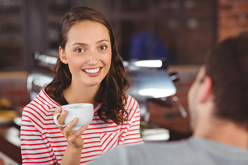 Portrait of smiling young woman enjoying coffee with her friend at coffee shop