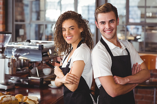 Portrait of smiling colleagues standing back to back at coffee shop