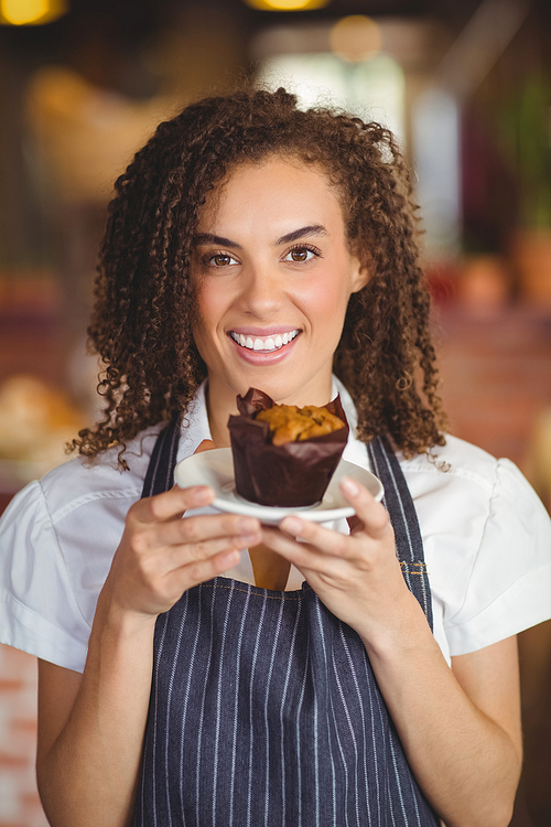 Portrait of a waitress holding a muffin at the coffee shop