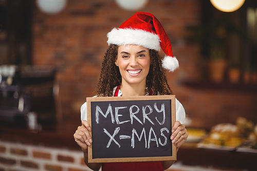 Portrait of a waitress with a chalkboard merry x-mas at the coffee shop