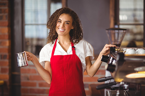 Portrait of a pretty waitress holding a jug at the coffee shop