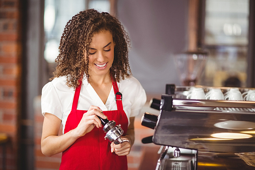 A smiling barista pressing coffee at the coffee shop