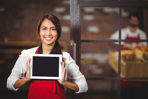 Portrait of a waitress showing a digital tablet at the coffee shop