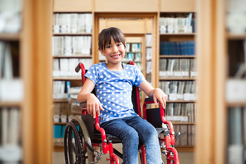 Cute disabled pupil smiling at camera in hall  against library