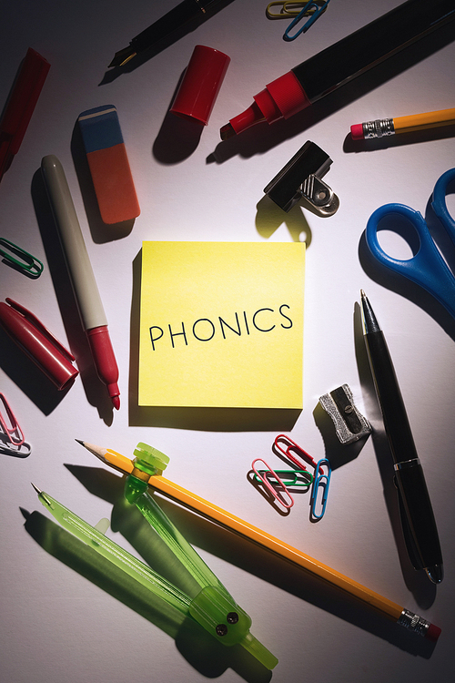 The word phonics against students table with school supplies