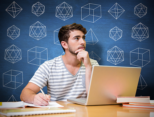 Student studying in the library with laptop against blue chalkboard
