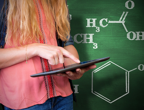 Student using tablet in library  against green chalkboard