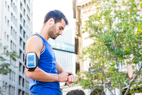 Handsome athlete setting heart rate watch in the city