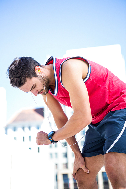 Exhausted athlete looking at his stopwatch on a sunny day