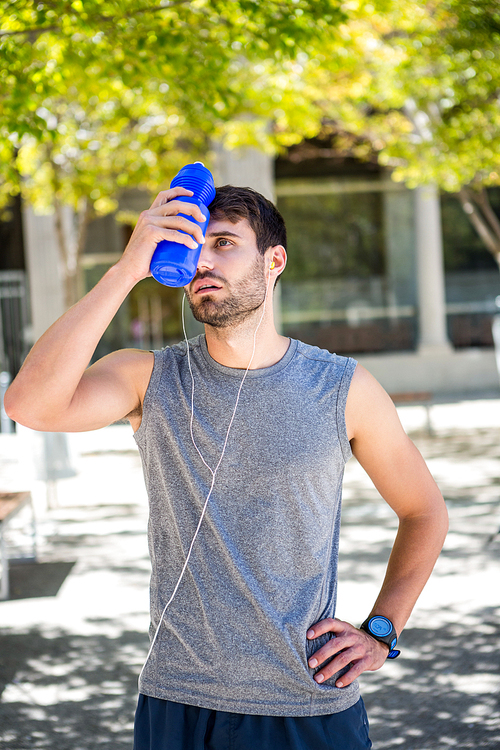 Exhausted runner putting a water bottle on head on a sunny day