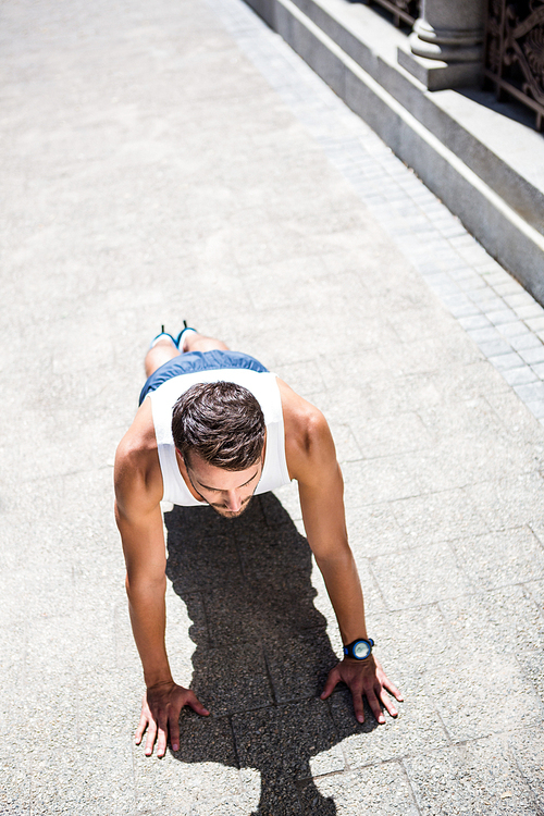 Handsome athlete doing push ups in the city