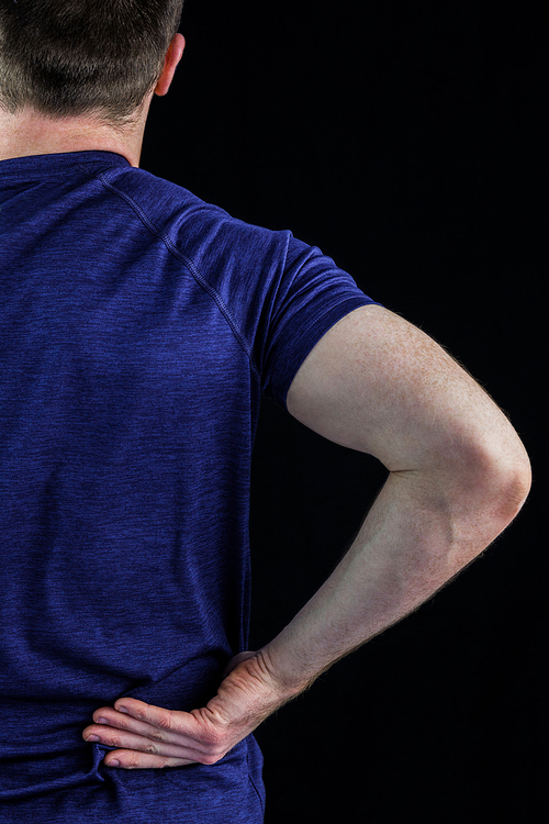 Rear view of a man with back pain over over black background