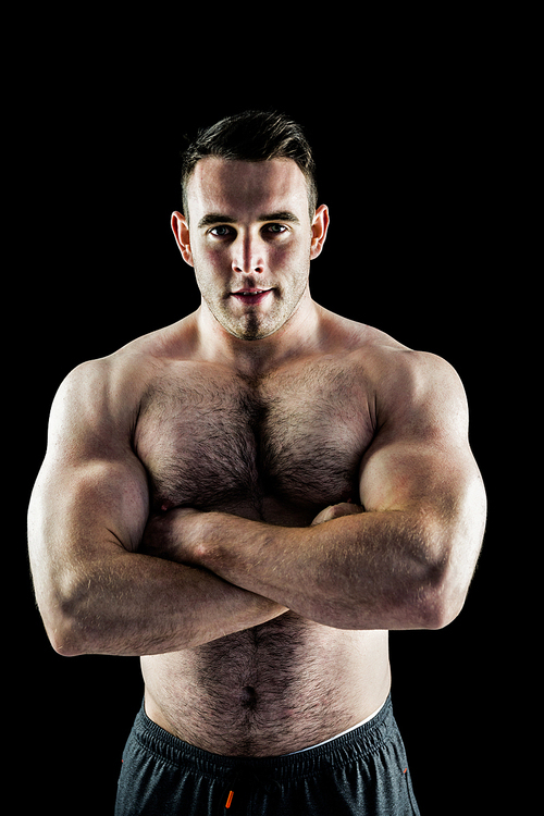 Handsome bodybuilder with arms crossed on black background