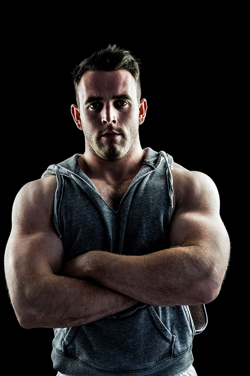 Handsome bodybuilder with arms crossed on black background