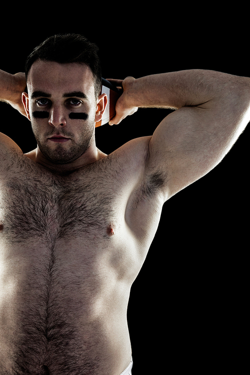 Shirtless American football player with ball on black background