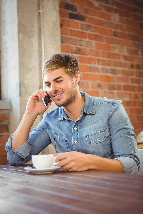 Handsome man having coffee and phoning at coffee shop