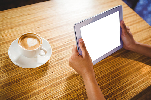 A businesswoman using a tablet and enjoying a coffee in a cafe