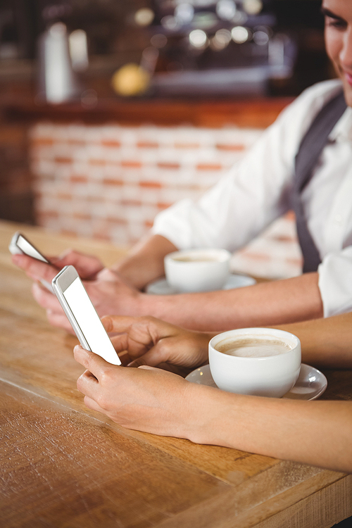 Cute couple sitting in cafe looking at smartphone on a sunny day