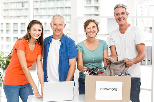 Portrait of smiling casual business people with donation box in the office