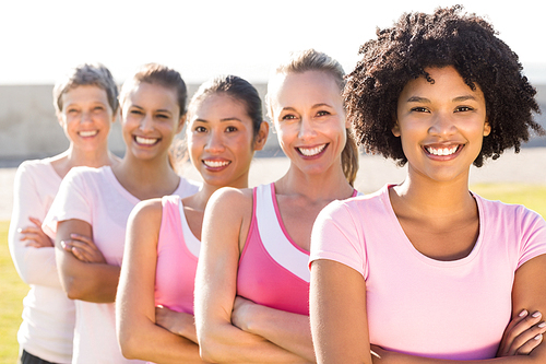 Portrait of smiling women wearing pink for breast cancer with arms crossed in parkland