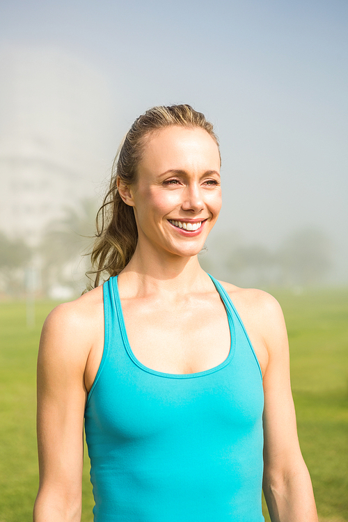 Smiling fit blonde looking away in parkland