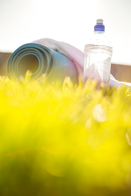 Water bottle, towel and exercise mat in the grass at promenade