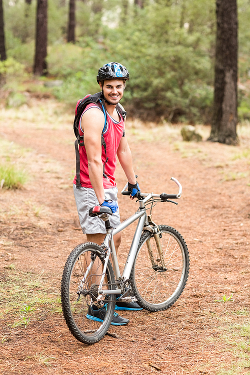 Happy handsome biker holding bike and  in the nature