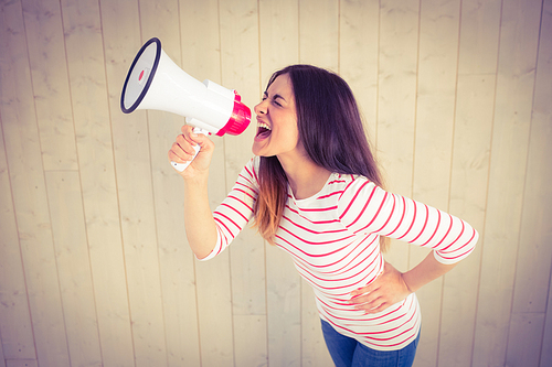 Pretty hipster shouting through megaphone on wooden planks background