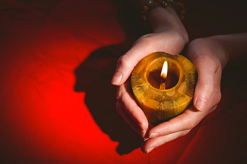 Fortune teller holding a candle on red table