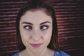 Pretty brunette with crossed eyes on red brick background