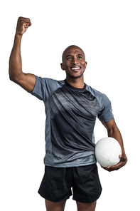 Happy sportsman with clenched fist holding rugby ball after victory standing over white background