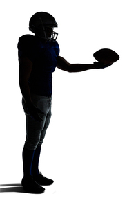 Side view of silhouette American football player holding ball against white background