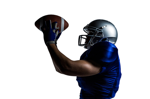 Side view of American football player catching ball against white background
