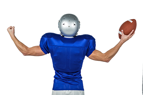 Rear view of American football player flexing muscles while holding ball against white background