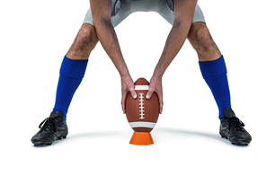 Low section of American football player placing the ball between his legs