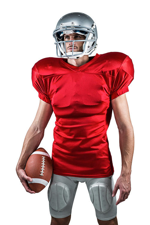 Confident American football player in red jersey looking away while holding ball against white background