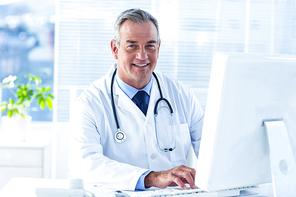 Portrait of male doctor workin on computer in clinic