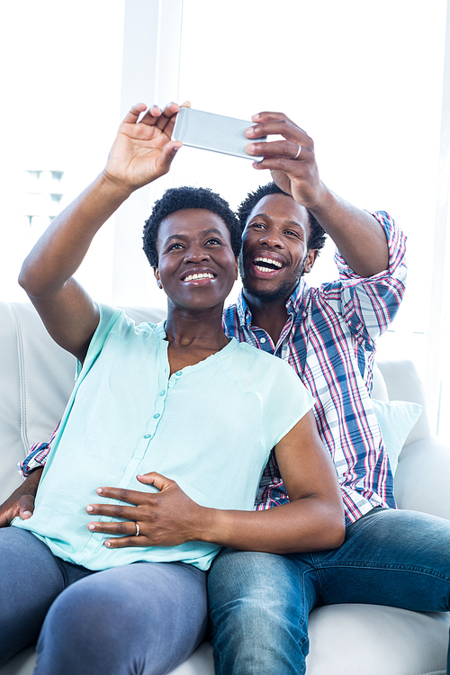 Smiling couple clicking selfie while relaxing at home